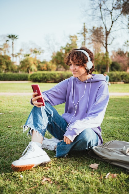 Girl listening to music in the park while holding her phone