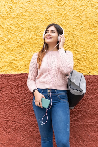 Girl listening to music through headphones on yellow and red background