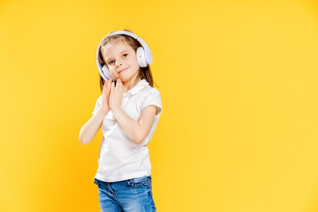 Ragazza che ascolta la musica in cuffie senza fili. ragazza danzante. piccola ragazza felice che balla alla musica. bambino sveglio che gode della musica da ballo felice.