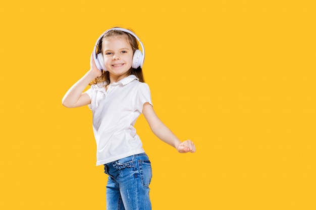 Girl listening to music in wireless headphones . Dancing girl. Happy small girl dancing to music. Cute child enjoying happy dance music.