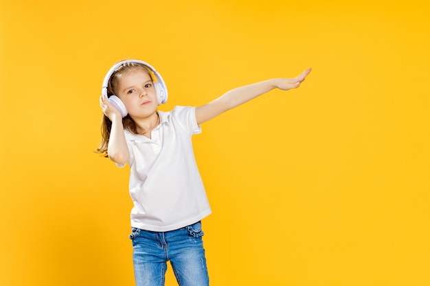 Girl listening to music in wireless headphones . Dancing girl. Happy small girl dancing to music. Cute child enjoying happy dance music.