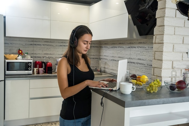 girl listening to online lessons in kitchen