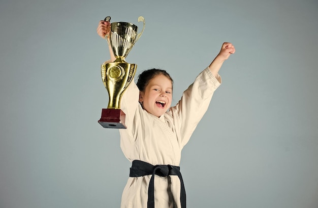 Girl little child in white kimono with belt Karate fighter child Karate sport concept Self defence skills Karate gives feeling of confidence Strong and confident small kid Victory and win