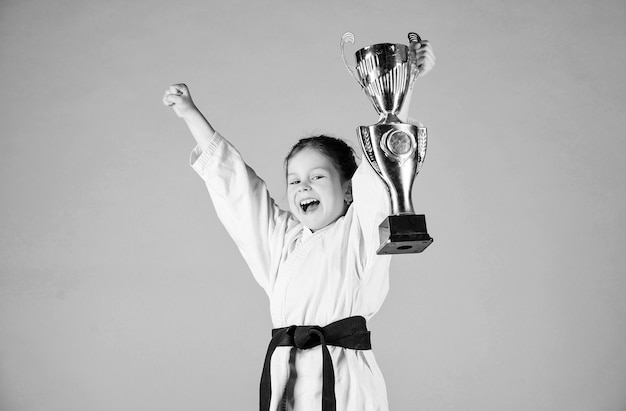 Girl little child in white kimono with belt Karate fighter child Karate sport concept Self defence skills Karate gives feeling of confidence Strong and confident small kid Victory and win