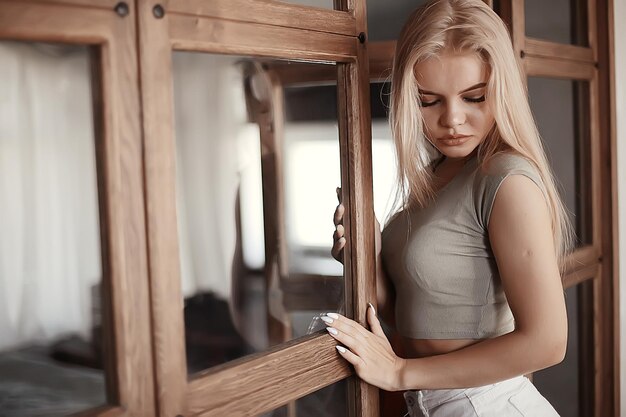 girl in a loft interior, modern house, windows, wall. young adult posing