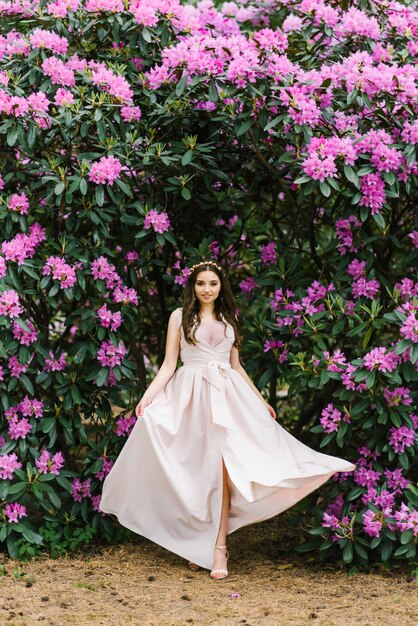 A girl in a long developing dress in the colors of rhododendron walks in the Park