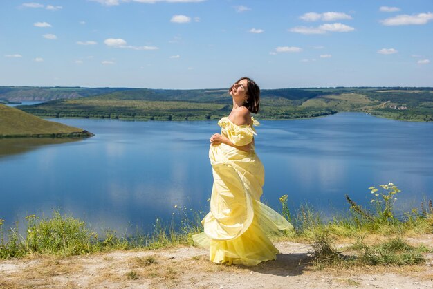 A girl in a long dress dancing on a cliff by the bay