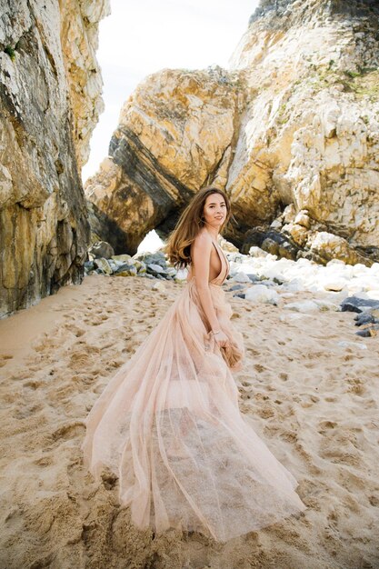 Girl in long dress near rocks and ocean