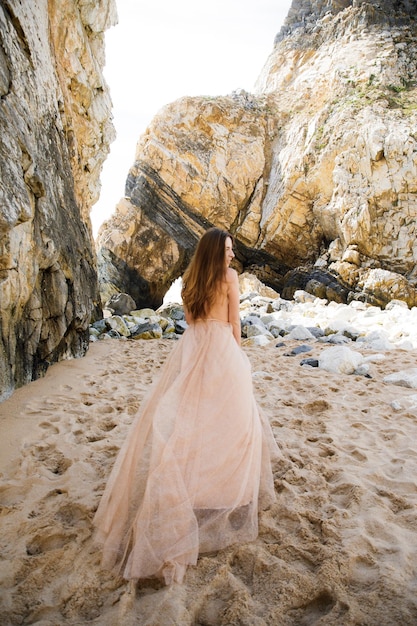 Girl in long dress near rocks and ocean