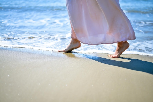 girl in a long skirt walks along the sea