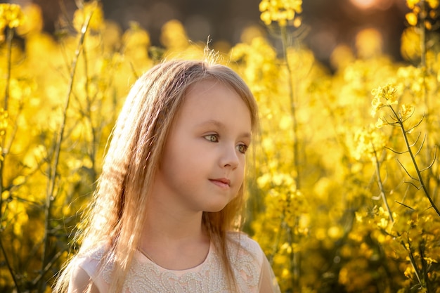 girl in a long white dress in a rapeseed field in summer