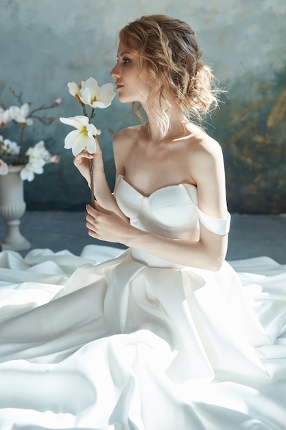 girl in a long white dress smelling flowers