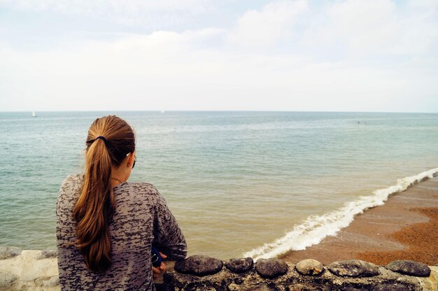 Foto ragazza che guarda la spiaggia