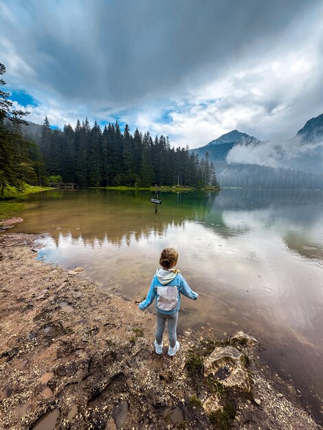 Girl looking on the beautiful Lake with mountains on background