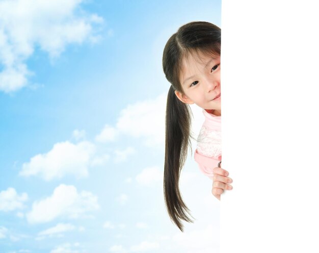 Girl looking at blank placard against sky