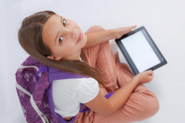 girl looking at the camera and holding a tablet in her hands