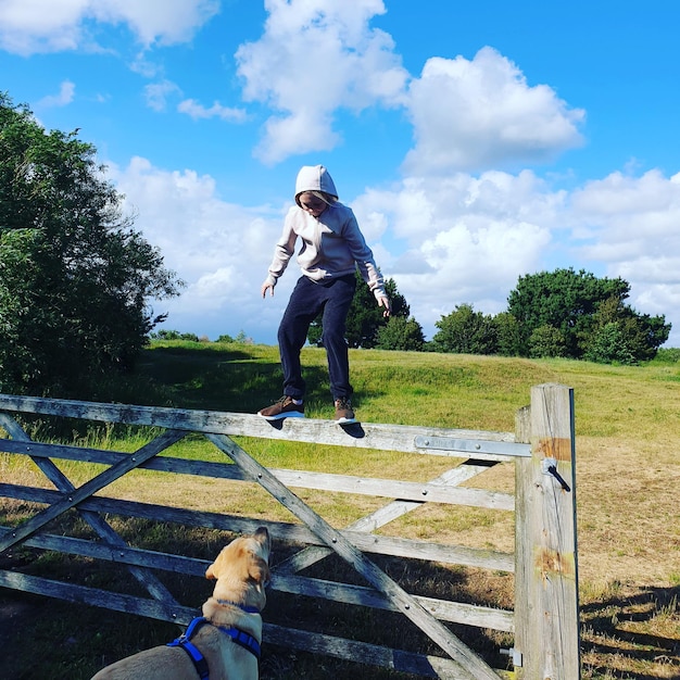 Girl looking at dog while standing on fence