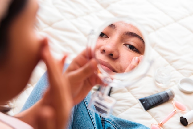 Una ragazza che si guarda il viso allo specchio