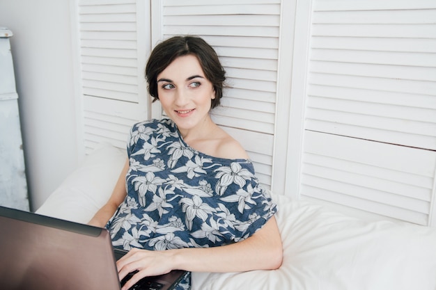 Girl looking at the laptop on the bed 