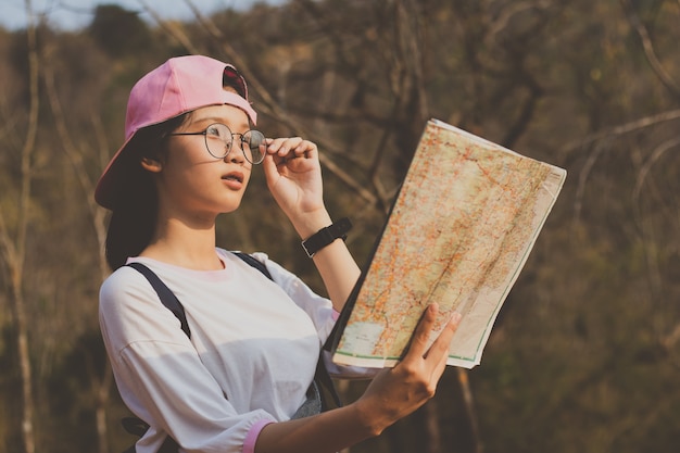 Foto ragazza guardando la mappa di viaggio nella foresta in vacanza.