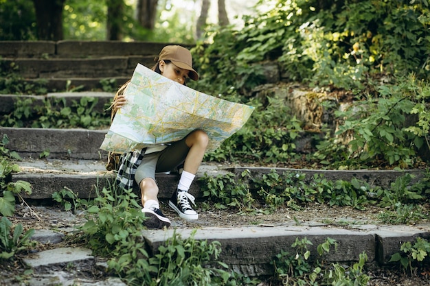 Girl looking at the map while walking in the forest