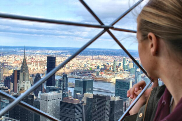 写真 空に照らして都市の近代的な建物を眺める少女