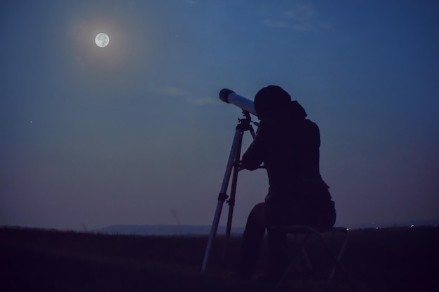 望遠鏡で月を見ている少女