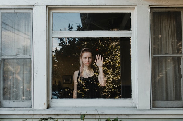 Girl looking out the window of her LA home during the covid-19 pandemic