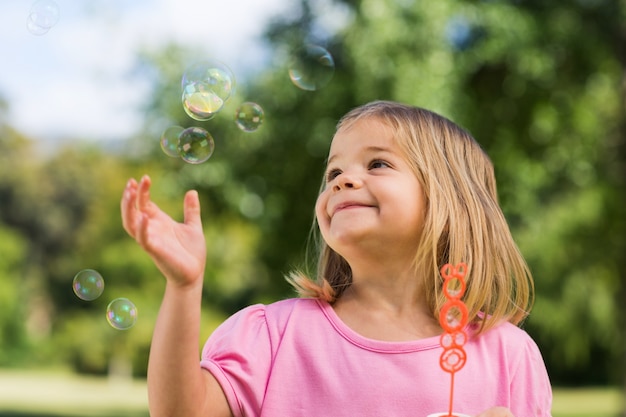 Photo girl looking at soap bubbles at park