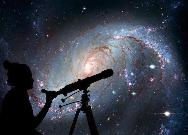 Girl looking at the stars with telescope. Stellar Nursery NGC 1672. Spiral galaxy in the constellation Dorado Elements of this image are furnished by NASA.