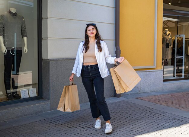 Girl  looking straight ahead in her arms hanging shopping bags Shopping in a shopping mall