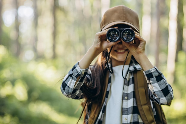 Photo girl looking through binoculars in park