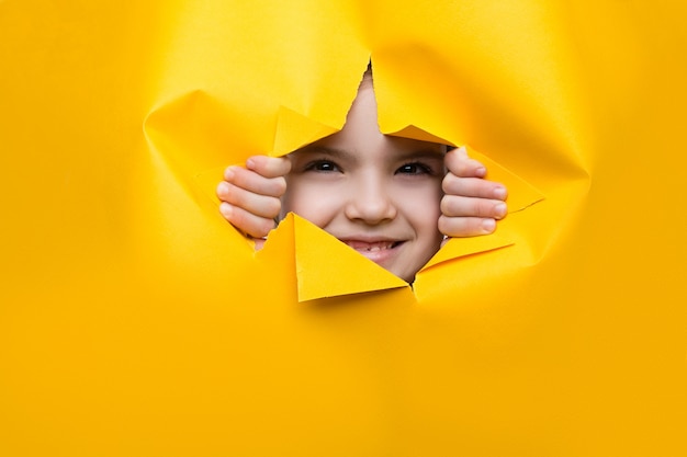 Girl looking through a hole in colored paper