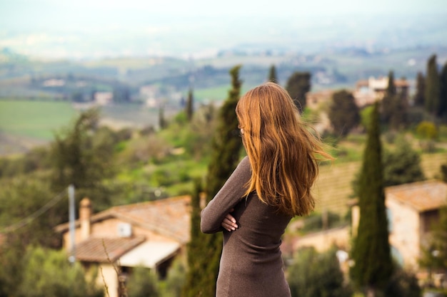 Girl looking at the tuscanian landscape with the hills and cypresses