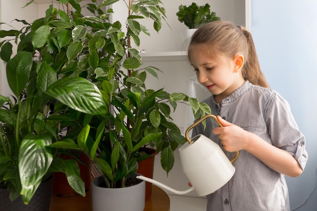 Girl looks after waters from watering can for flowers and admires the flowers home garden concept