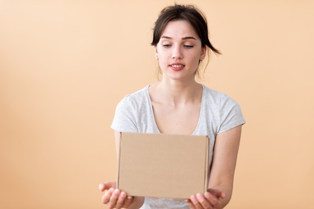 The girl looks at the cardboard box with a smile and interest