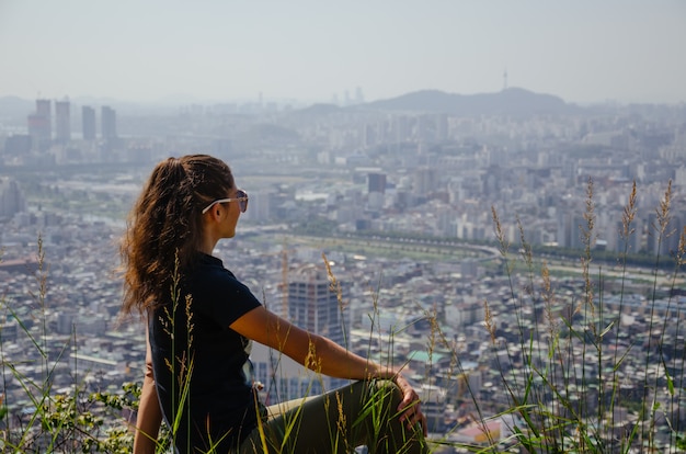 Girl looks to the city from mountain