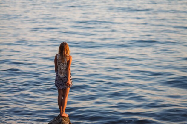 The girl looks at the sea sunset