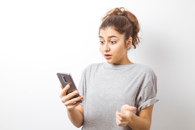 The girl looks at the smartphone in surprise. 