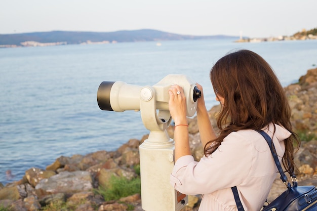 女の子は海を望遠鏡で見ています