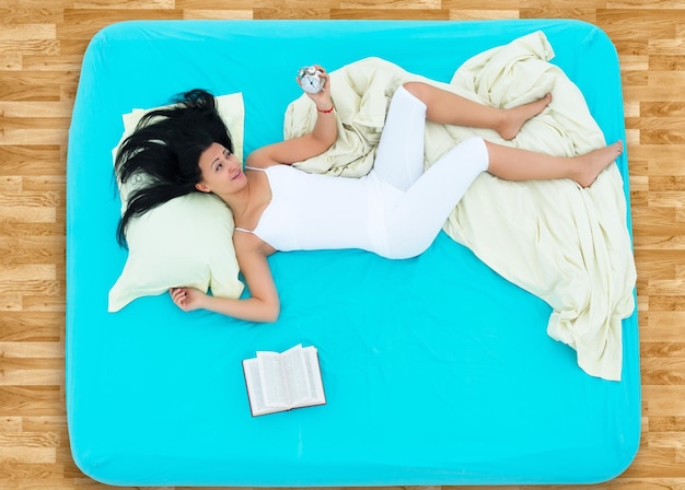 Foto ragazza sdraiata a letto e dormire dopo aver letto un libro vista dall'alto