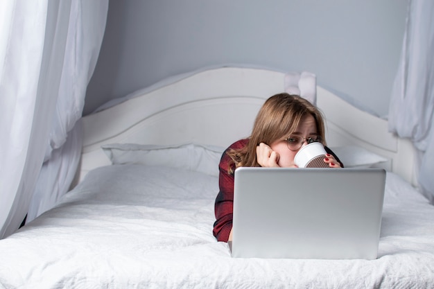 Girl lying in bed with a laptop