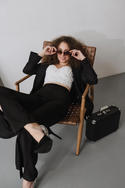 Girl lying on a brown chair in a black classic suit