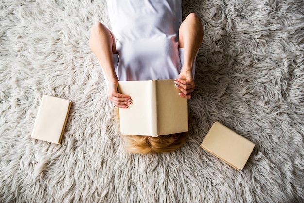 Foto ragazza sdraiata sul tappeto e leggendo un libro