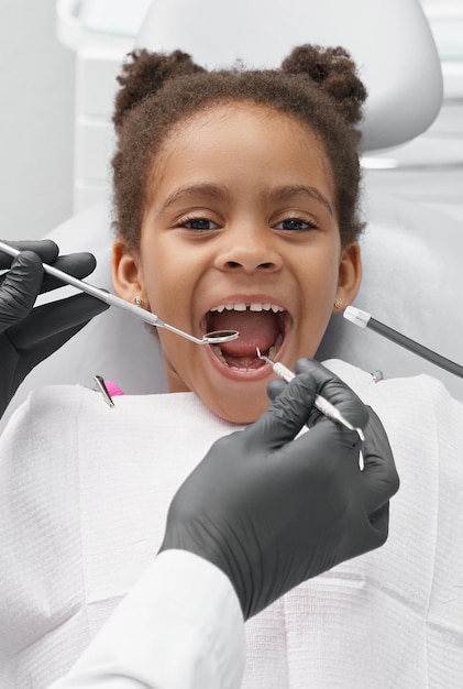 Girl lying on dentist chair with open mouth in clinic