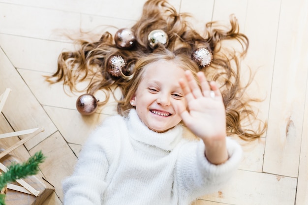 Ragazza sdraiata sul pavimento tra le palle di capelli per l'albero di natale