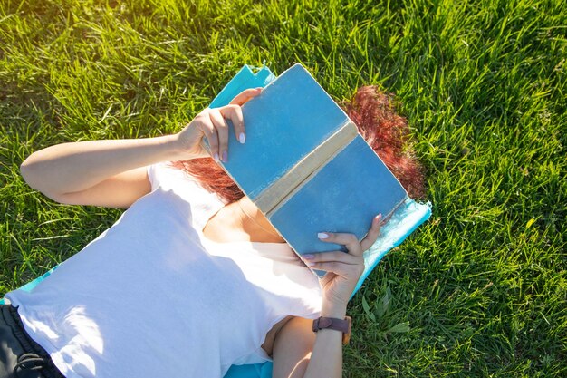 Girl lying on grass reading book