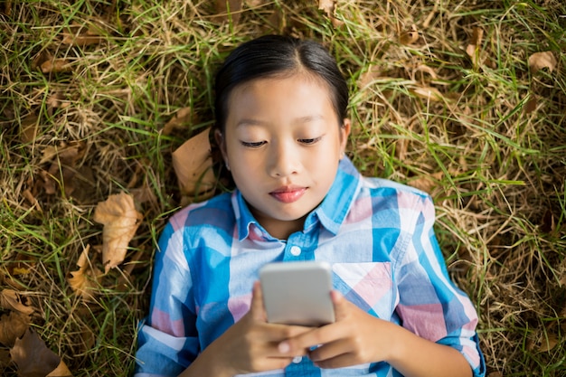 Ragazza che si trova sull'erba e che per mezzo del telefono cellulare