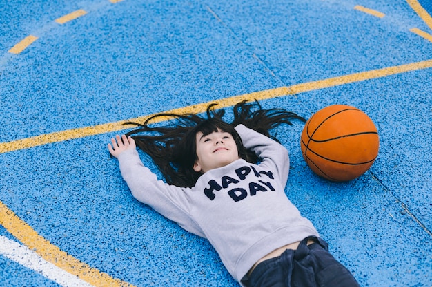 Photo girl lying near basketball ball