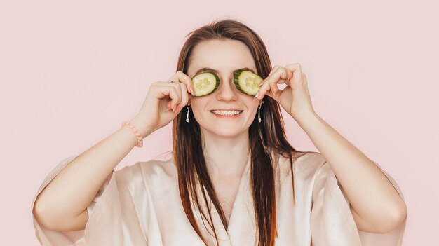 Girl make homemade face beauty masks. Cucumbers for the freshness of the skin around the eyes 